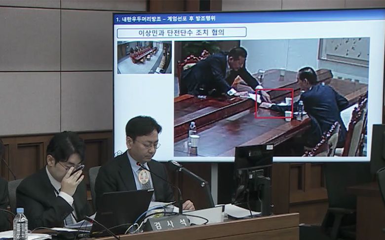 2025년 10월 13일 서울중앙지법 형사합의33부(부장판사 이진관) 심리로 열린 한덕수 전 국무총리 2차 공판에서 특검이 제시한 12·3 비상계엄 당일 대통령실 폐쇄회로(CC)TV 영상 화면에 한 전 총리(오른쪽)와 이상민 전 행정안전부 장관이 계엄 관련 문건을 주고받고 있는 모습이 재생되고 있다. 법원 공판 중계 화면 캡처