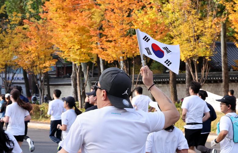 9일 서울 중구 서울광장에서 열린 ‘2025 자유민주 마라톤’에서 참가자가 태극기를 들고 달리고 있다. 출처=뉴스1