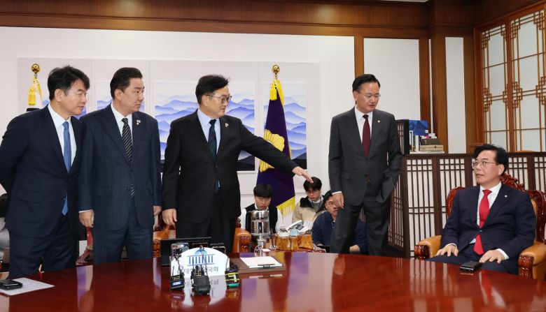 우원식 국회의장(가운데)이 27일 서울 여의도 국회 의장실에서 열린 여야원내대표 회동에서 송언석 국민의힘 원내대표(오른쪽)가 기념촬영을 거부하고 자리에 앉아버리자 자리에 일어나라고 요청하고 있다. 왼쪽부터 문진석 더불어민주당 원내수석부대표, 김병기 원내대표, 우 의장, 유상범 국민의힘 원내수석부대표, 송 원내대표. 2025.11.27/사진공동취재단