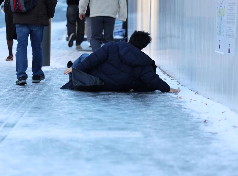 폭설 후 한파로 도로 곳곳이 얼어붙은 5일 오전 서울 광화문역 일대에서 한 시민이 빙판길에 미끄러져 넘어지고 있다.  2025.12.5 뉴스1