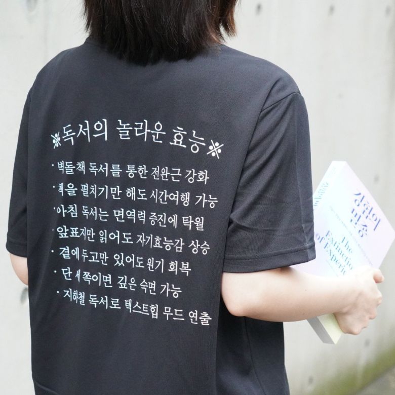 ‘독서의 놀라운 효능’을 유머러스하게 쓴 티셔츠.  ‘경험의 멸종’의 굿즈로 판매해 완판됐다.        어크로스 제공