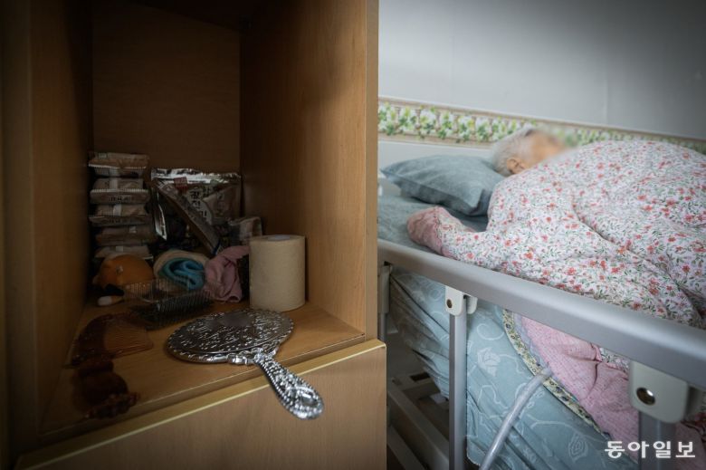 전동침대에 누워 자는 옥분의 옆으로 은색 손거울이 엎어져 있다.