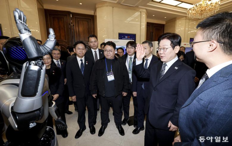 이재명 대통령이 7일 중국 상하이 국제회의중심에서 열린 한중 벤처 스타트업 서밋 행사에서 중국 기업 아지봇의 휴머노이드 로봇과 악수를 하고 있다.  상하이=송은석 기자 silverstone@donga.com
