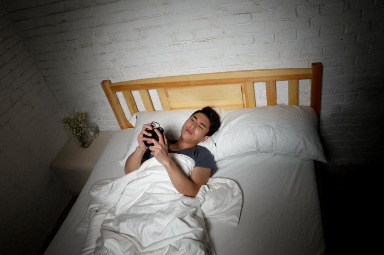 잠자리에 누운 채 스마트폰을 사용하는 습관은 잠드는 시간을 늦출 뿐 아니라, 깊은 수면 진입을 방해해 다음 날 낮 졸림으로 이어질 수 있다. 게티이미지뱅크