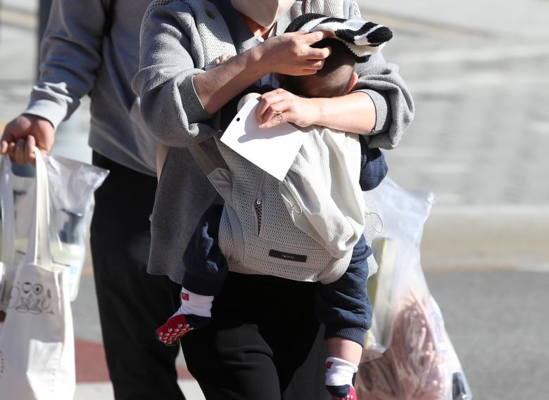 엄마가 찬바람을 가리기 위해 아기에게 털모자를 씌워주고 있다. 2025.12.4 뉴스1