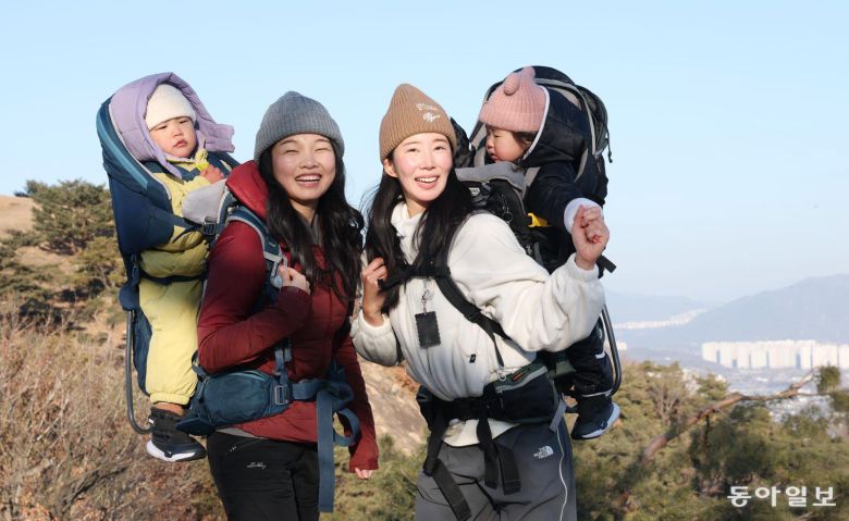 오언주 베이비하이킹클럽(베하클) 회장(왼쪽)과 김지영 씨가 각각 아들과 딸을 업고 서울 광진구 아차산 해맞이코스 1보루에 올라 활짝 웃고 있다. 신원건 기자 laputa@donga.com