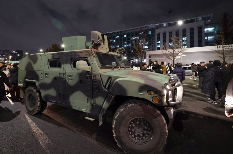 지난해 12월 4일 새벽 서울 여의도 국회 앞 계엄군 차량 뒤로 군 헬기가 경내로 비행하고 있다./뉴스1