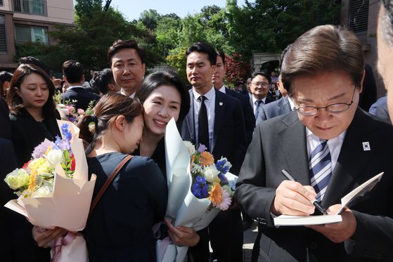 이재명 대통령과 김혜경 여사가 4일 인천 계양구 사저를 출발하다 이 대통령이 책에 서명을, 김 여사가 한 주민과 포옹을 하고 있다. 〈사진=연합뉴스〉