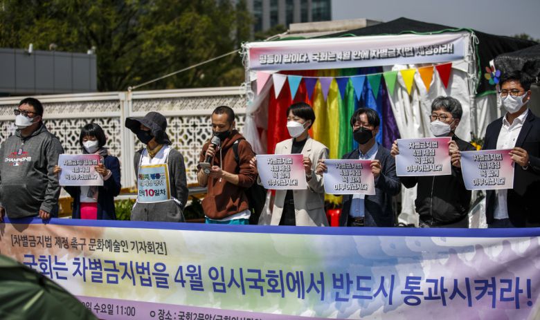 차별금지법 제정을 촉구하는 문화예술인들이 20일 서울 여의도 국회 앞에서 열린 기자회견에서 피켓을 들고 있다. 뒤에는 단식농성장이 보인다.