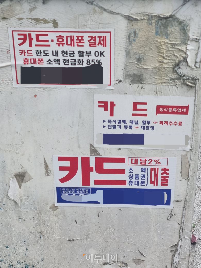 경기도의 한 상가 앞 기둥에 휴대폰 소액결제 현금화, 신용카드 현금화 등 '불법 현금화' 광고 전단 세 장이 붙어있다. 위에 두 전단은 '대출' '일수' 등의 표현이 없어 전화번호 이용중지 제재가 불가능하다. 반면, 맨 아래 전단은 '대출'이라는 표현이 있어 신고 및 제재 대상이 된다. 거리에서 쉽게 볼 수 있는 불법 현금화 광고 전단에는 대부분 '대출'이라는 표현이 없다.
