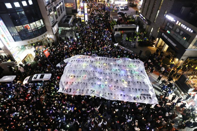 12일 서울 영등포구 국민의힘 당사 앞에서 윤석열 대통령 탄핵 촉구 촛불집회 참가자들 지난 7일 국회 탄핵 표결에 불참한 국민의힘 의원들 사진 현수막을 찢고 있다. 2024.12.12.