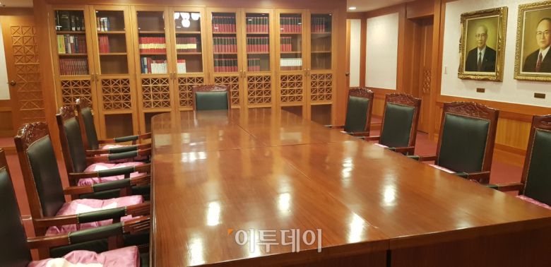 역대 헌법재판소장 초상화들이 벽면을 채우고, 평의를 위한 대형 탁자와 의자 9개가 놓여있는 ‘헌법재판소 재판관 평의실’