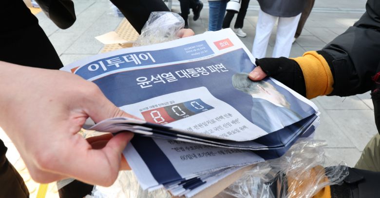 헌법재판소가 윤석열 전 대통령 탄핵심판에 대해 인용을 선고한 4일 서울 종로구 광화문역 출입구에서 시민들이 선고 소식을 실은 신문 호외를 가져가고 있다. 연합뉴스