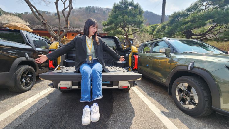 무쏘 EV 데크 테일게이트에 기자가 앉은 모습.