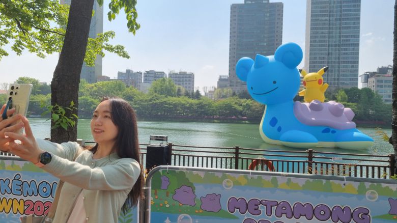 28일 오전 서울 송파구 석촌호수에서 한 고객이 메타몽이 변신한 16m 크기의 라프라스와 피카츄 앞에서 사진을 찍고 있다.