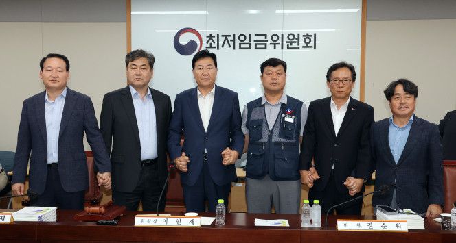 10일 정부세종청사에서 열린 제12차 전원회의에서 내년 최저임금을 시간당 1만320원으로 17년만에 합의로 결정한 공익위원-사용자위원-근로자위원들이 손을 잡고 기념촬영을 하고 있다. 왼쪽부터 하헌제 상임위원, 이인재 위원장, 사용자위원인 류기정 한국경영자총협회 전무, 근로자위원인 류기섭 한국노총 사무총장, 사용자위원인 이명로 중소기업중앙회 인력정책본부장, 공익위원인 권순원 숙명여대 교수. 2025.7.11