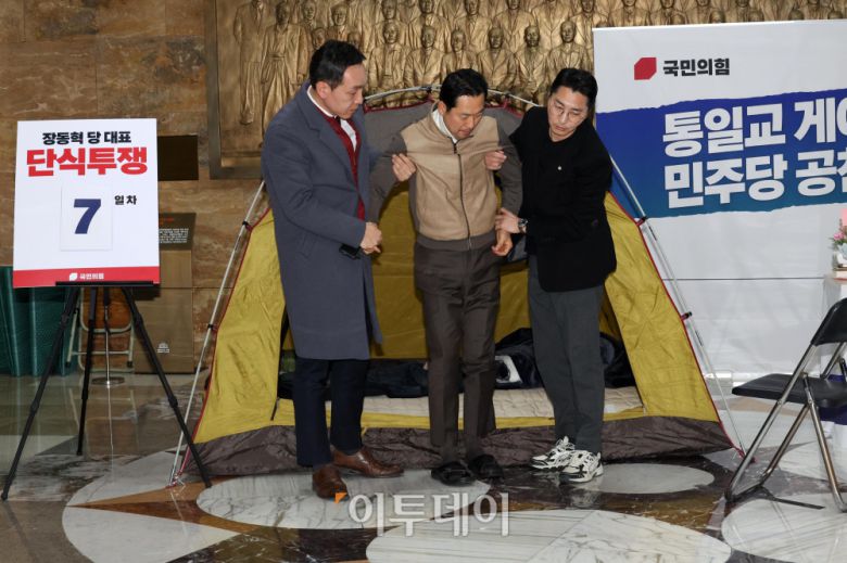 통일교·공천헌금 '쌍특검' 수용을 요구하며 단식 일주일째를 맞은 장동혁 국민의힘 대표가 21일 서울 여의도 국회 로텐더홀 단식 농성장에서 의원들의 부축을 받고 있다. 고이란 기자 photoeran@