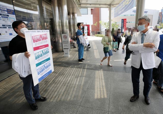 ▲전국의사 2차 총파업을 하루 앞둔 25일 서울 종로구 서울대학교병원에서 김연수 서울대병원장(오른쪽)이 전임의들의 피켓 시위를 바라보고 있다. ⓒ연합뉴스