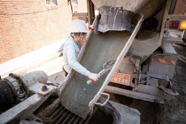 ▲<프레시안>은 지난달 24일 부산 기장군의 한 건설현장을 찾아 레미콘 기사로 25년째 일하고 있는 정정숙씨를 만났다. 레미콘을 운반하자마자 레미콘이 흐른 자리에 붙어 굳지 않도록 통로를 긁어내는 정숙씨. ⓒ황지현