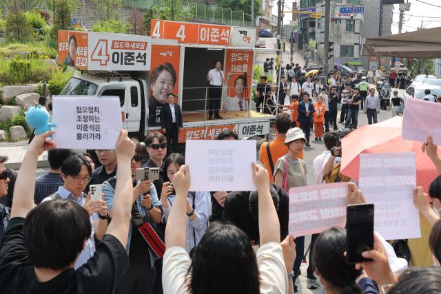▲개혁신당 이준석 대선 후보가 30일 서울 동작구 중앙대학교에서 유세 중인 가운데 일부 학생들이 최근 이 후보의 TV토론 여성 신체 관련 발언을 규탄하며 팻말을 들고 있다. ⓒ연합뉴스