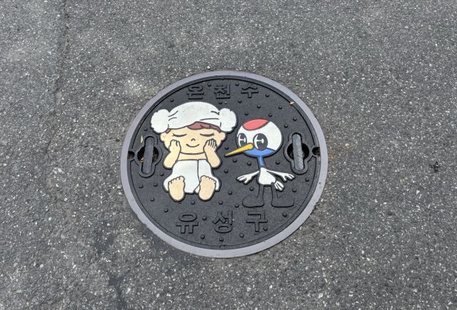 ▲ 대전 유성구가 온천관로 시설에 설치한 유성구 대표 캐릭터 ‘유성이’와 ‘유온이’가 그려진 맨홀 뚜껑 ⓒ대전 유성구