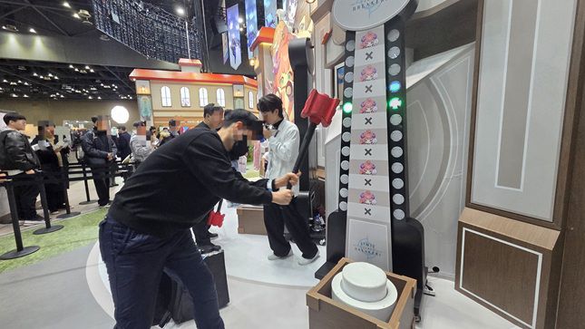 한 관람객이 5일 일산 킨텍스 제1전시장에서 열린 'AGF 2025' 내 '리밋 제 브레이커스' 부스에서 에르카의 괴력망치를 체험하고 있다. /사진=비즈워치