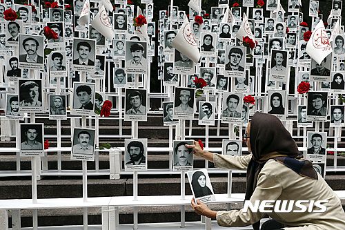 【뉴욕=AP/뉴시스】미국 뉴욕 유엔본부 앞에서 2016년 9월 20일 한 여성이 이란에서 처형된 약 3만명의 사진을 일일이 붙이는 시위에 참가하고 있다.  이 시위를 조직한 이란미국커뮤니티기구는 이란 정부의 인권 탄압을 비판하고 민주적 변화를 촉구했다. 2025.06.19.