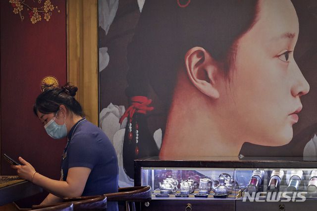 [베이징=AP/뉴시스]14일(현지시간) 중국 베이징의 한 기념품 가게에서 신종 코로나바이러스 감염증(코로나19) 예방을 위해 마스크를 쓴 직원이 스마트폰을 검색하고 있다. 2020.07.14.