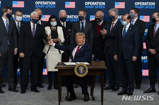 [워싱턴=AP/뉴시스] 도널드 트럼프 미국 대통령이 8일(현지시간) 신종 코로나바이러스 감염증(코로나19) 백신 공급에서 '미국 우선주의'를 강조한 행정명령에 서명했다. 서명식에서 트럼프 대통령이 마이크 펜스 부통령에게 펜을 건네고 있다. 2020.12.09.