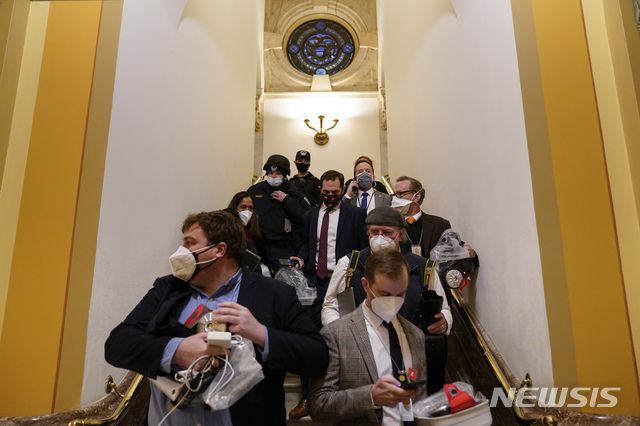 [워싱턴=AP/뉴시스]6일(현지시간) 미  의사당에 난입한 도널드 트럼프 대통령 지지자들이 하원에 침입하려하자 안에 있던 의원들이 대피하고 있다. 2021.01.07.