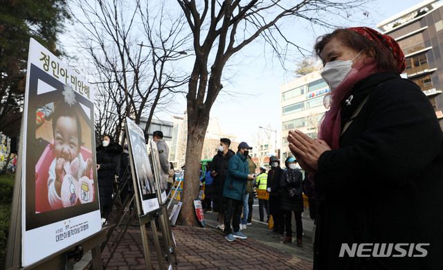 [서울=뉴시스]홍효식 기자 = 16개월 여아 '정인이'의 입양부모 5차 공판이 열리는 지난달 3일 서울 양천구 서울남부지방법원 앞에서 한 시민이 정인이 사진을 보며 기도하고 있다. 2021.03.03. yesphoto@newsis.com