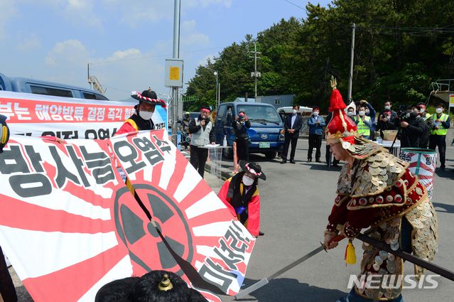 [남해=뉴시스]차용현 기자 = 30일 오전 경남 남해군 미조항 인근 방파제에서 열린 일본 후쿠시마 원전 오염수 해양 방류 규탄대회에서 이순신 장군으로 분장한 한 어민이 욱일기를 칼로 자르고 있다. 2021.04.30. con@newsis.com