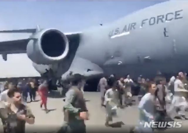 [카불=AP/뉴시스] 16일(현지시간) 아프가니스탄 카불의 하미드 카르자이 국제 공항에서 수백 명의 아프간 사람들이 활주로를 따라 이동하는 미 공군 C-17 수송기에 몰려들고 있다. 탈레반이 점령한 아프간을 탈출하려는 아프간 시민 수천 명이 이날 공항 활주로에 몰려들어 일부는 필사적으로 미군 항공기에 매달리다가 추락해 사망한 것으로 알려졌다. 2021.08.17.