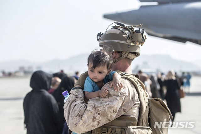 [카불=AP/뉴시스] 21일(현지시간) 아프가니스탄 카불의 하미드 카르자이 국제공항에서 아프간 대피 작전 중인 미 해병대 병사가 한 아프간 아이를 안아 달래고 있다. 2021.08.23.