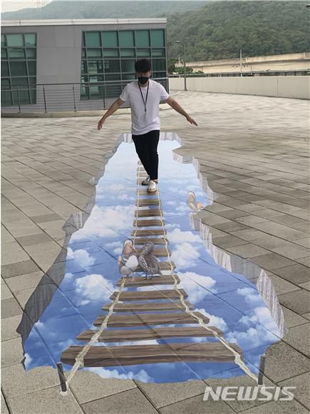 [용인=뉴시스]경기 용인도시공사가 고보라이트와 트릭아트를 설치해 둘레길 주변의 단조로움을 개선했다. 사진은 착시효과를 낸 둘레길을 걷고 있는 시민