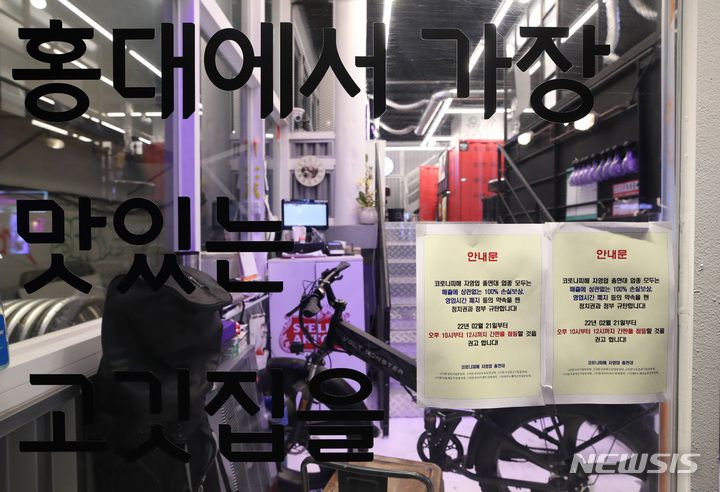 [서울=뉴시스] 조수정 기자 = 한국외식업중앙회와 한국유흥음식업중앙회 등 14개 소상공인 단체로 구성된 코로나피해자영업총연합(코자총) 소속 서울 홍대입구역 인근 음식점 상인들이 21일 코로나19 영업 제한시간인 오후 10시 이후 영업점 불을 켜고 점등 시위를 하고 있다. 유리창에는 간판 점등을 권고하는 안내문이 붙어 있다. 코자총은 영업시간 제한 폐지와 자영업자 실질적인 손실보상 100% 지급 등의 약속을 깬 정치권과 정부를 규탄하며 간판 및 영업점 점등시위를 시작했다. 2022.02.21. chocrystal@newsis.com
