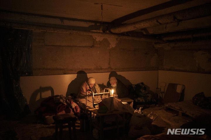 [이르핀=AP/뉴시스] 13일(현지시간) 우크라이나 키이우 외곽 이르핀에서 두 노인이 방공호로 쓰이는 지하실에 숨어 촛불을 밝히고 있다. 2022.03.14.