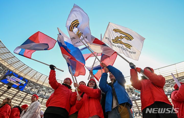 [모스크바=AP/뉴시스]18일(현지시간) 모스크바에서 열린 크름(크림)반도 러시아 합병 기념 콘서트에서 참가자들이 러시아군 상징인 'Z' 문양이 새겨진 깃발을 흔들고 있다. 2022.3.18.