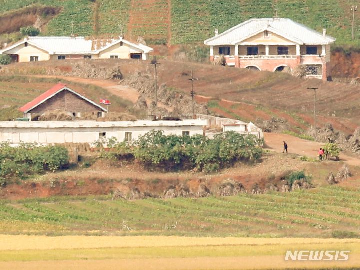 [서울=뉴시스] 조수정 기자 = 북한 노동당 77주년 창건일인 10일 오전 경기 파주시 오두산 통일전망대에서 바라본 북한 황해북도 개풍군 탈곡장(왼쪽) 옆으로 주민들이 밭 수확물을 나르고 있다. 2022.10.10. chocrystal@newsis.com