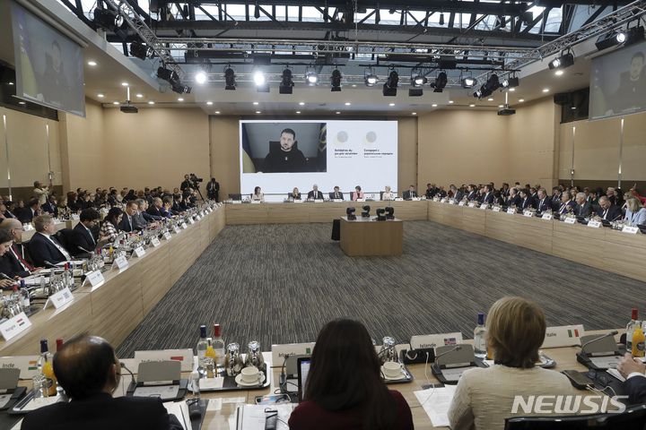 [파리=AP/뉴시스] 볼로디미르 젤렌스키(위) 우크라이나 대통령이 13일(현지시간) 프랑스 파리에서 열린 '우크라이나 국민과의 연대' 국제회의에 화상으로 참여하고 있다. 프랑스 정부는 우크라이나의 인프라 재건 지원을 위해 물자와 자금을 모으는 국제회의를 개최했다. 2022.12.13.