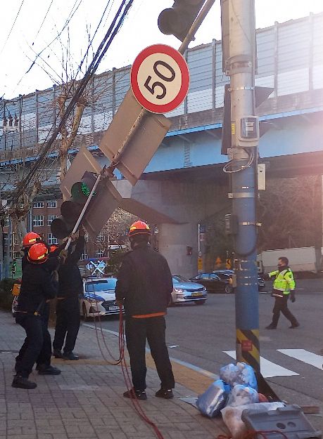 [부산=뉴시스] 부산지역에 한파·강풍주의보가 발효된 24일 부산진구의 한 도로 신호등이 강풍에 꺾여 부산소방이 안전조치를 실시하고 있다. (사진=부산소방재난본부 제공). 2023.01.24. photo@newsis.com  *재판매 및 DB 금지