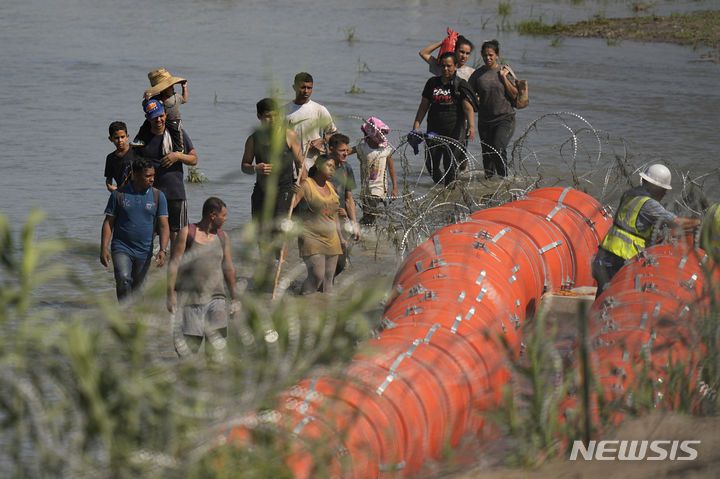 [리오 그란데( 미 텍사스주)=AP/뉴시스] 멕시코에서 리오 그란데 강을 건너 미국으로 오려던 이민들이 2023년 7월 11일 텍사스주가 이글 패스 시의 강물위에 거대한 부표국경선을 설치하는 장소에 도착해 이를 구경하고 있다. 2024. 06. 21.