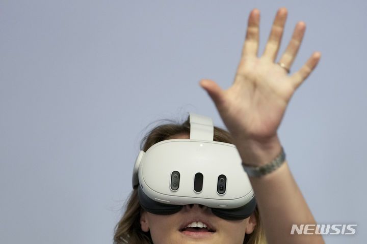 [멘로파크=AP/뉴시스] 27일(현지시각) 미 캘리포니아주 멘로파크 메타 본사에서 메타 커넥트 개발자 콘퍼런스가 열려 한 참석자가 이날 공개된 VR 헤드셋 '메타 퀘스트3'를 체험하고 있다. 퀘스트3에는 앱에서 헤드셋의 아무 부분이나 두 번 탭하면 가상 세계에서 벗어나게 해주는 '패스스루' 기능과 이미지를 더 선명하게 만들고 해상도를 높여 주는 '팬케이크 렌즈'가 장착됐다. 메타는 퀘스트3가 고립감을 줄여 장시간 사용하기에 편안하게 만들었다고 밝혔다. 2023.09.28.