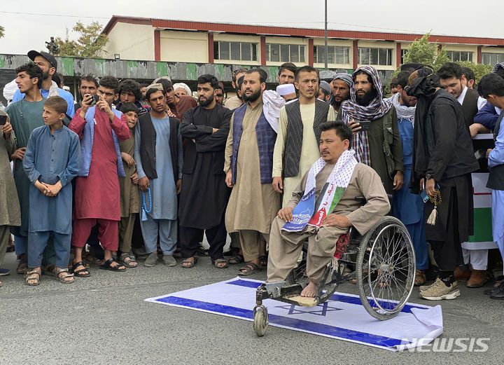 [카불=AP/뉴시스] 10월13일 아프가니스탄 카불에서 휠체어에 앉은 한 아프간 남성이 이스라엘 국기를 밟고 이스라엘의 가자지구 공습에 반대하는 시위에 참여해 팔레스타인과의 연대를 보여주고 있다. 2023. 11.06