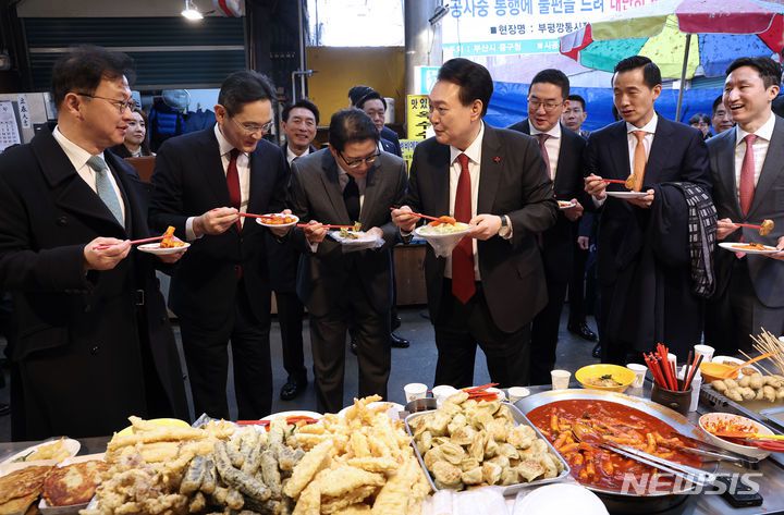 [부산=뉴시스] 전신 기자 = 윤석열 대통령이 6일 부산 중구 깡통시장을 방문해 기업인들과 떡볶이를 맛보며 대화하고 있다. 왼쪽부터 최재원 SK 수석부회장, 이재용 삼성전자 회장, 조현준 효성 그룹 회장, 윤 대통령, 구광모 LG그룹 회장, 김동관 한화그룹 부회장, 정기선 HD현대 부회장. (대통령실통신사진기자단) 2023.12.06. photo1006@newsis.com