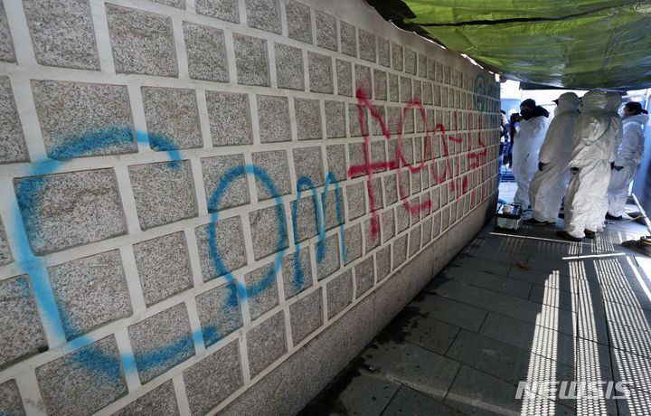 [서울=뉴시스] 배훈식 기자 = 문화재청 작업자들이 17일 오전 서울 종로구 경복궁 서편 담장에 칠해진 낙서 제거 작업을 하고 있다. (공동취재) 2023.12.17. photo@newsis.com