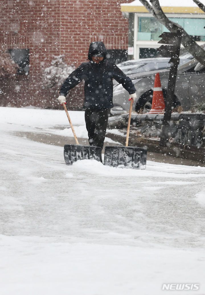 [서울=뉴시스] 김근수 기자 = 서울지역에 대설주의보가 내려진 30일 서울 종로구 세종대로 일대에서 한 건물 관리인이 눈을 치우고 있다. 2023.12.30. ks@newsis.com