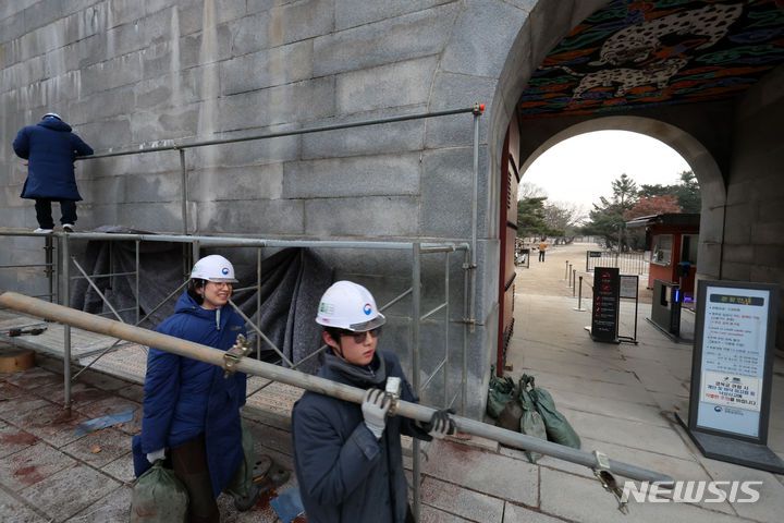 [서울=뉴시스] 조성우 기자 = 문화재청 관계자들이 4일 오전 낙서 복구 작업을 위해 설치됐던 서울 종로구 경복궁 영추문 담벼락 가림막 제거 작업을 하고 있다. 2024.01.04. xconfind@newsis.com