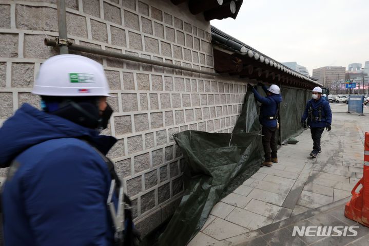 [서울=뉴시스] 조성우 기자 = 문화재청 관계자들이 4일 오전 낙서 복구 작업을 위해 설치됐던 서울 종로구 경복궁 영추문 담벼락 가림막 제거 작업을 하고 있다. 2024.01.04. xconfind@newsis.com