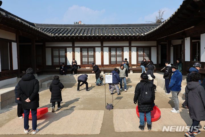 [서울=뉴시스] 권창회 기자 = 설날인 10일 오후 서울 중구 남산골한옥마을에서 열린 '청룡이 복 나르샤' 설축제에서 시민들이 팽이치기를 하고 있다. 2024.02.10. kch0523@newsis.com